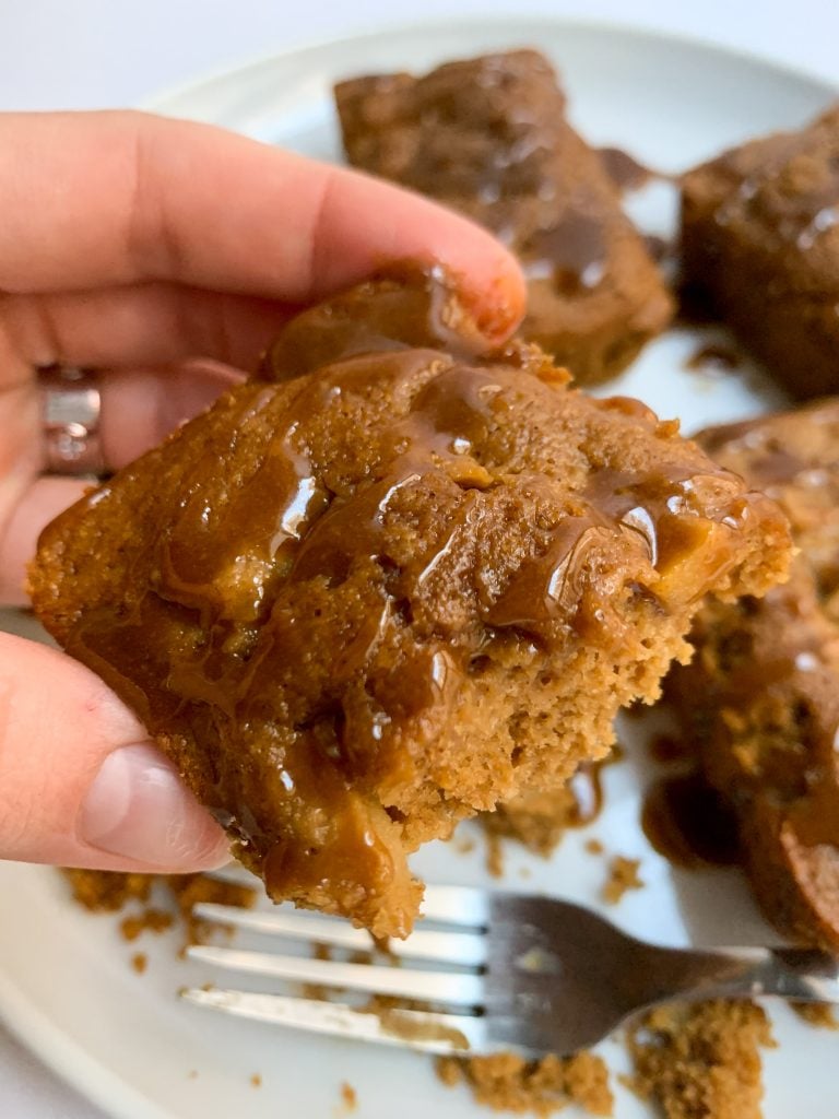 hand holding a loaf over caramel apple loaves with a caramel drizzle on a white plate