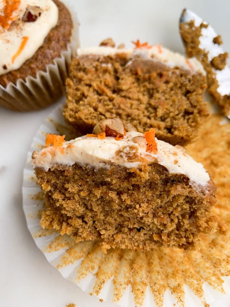 healthier carrot cake cupcakes on w a white board, one cut open, a knife on the side