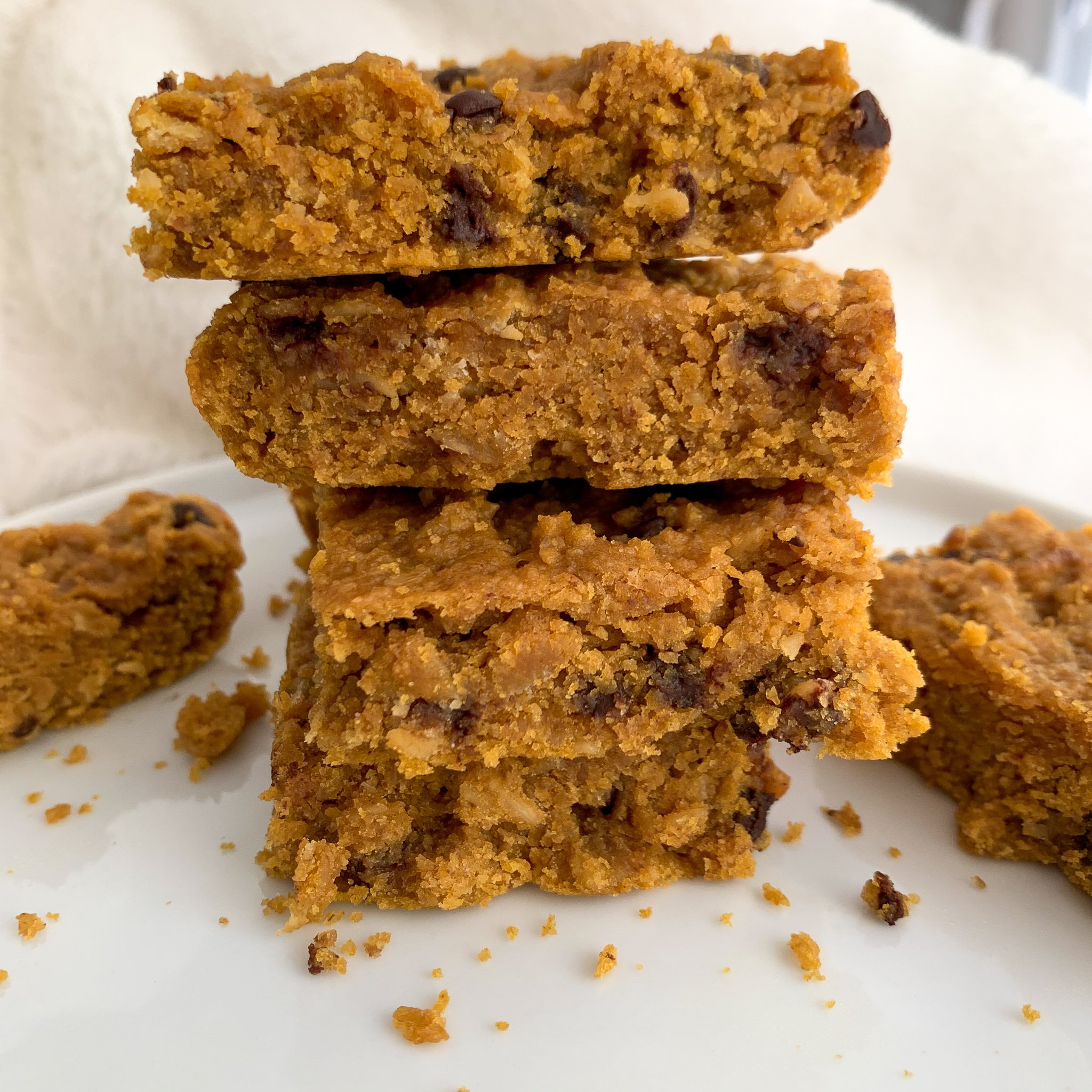 peanut butter and pumpkin chocolate chip oat bars on a white plate with a white background