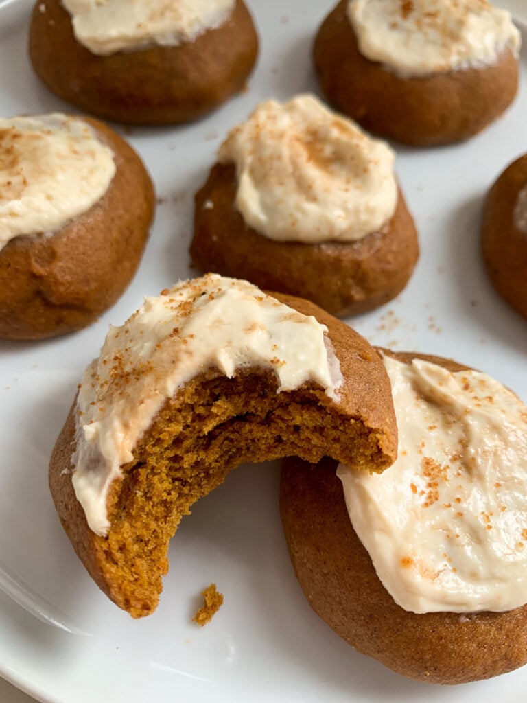 whole wheat pumpkin cookies with a maple cream cheese frosting on a white plate