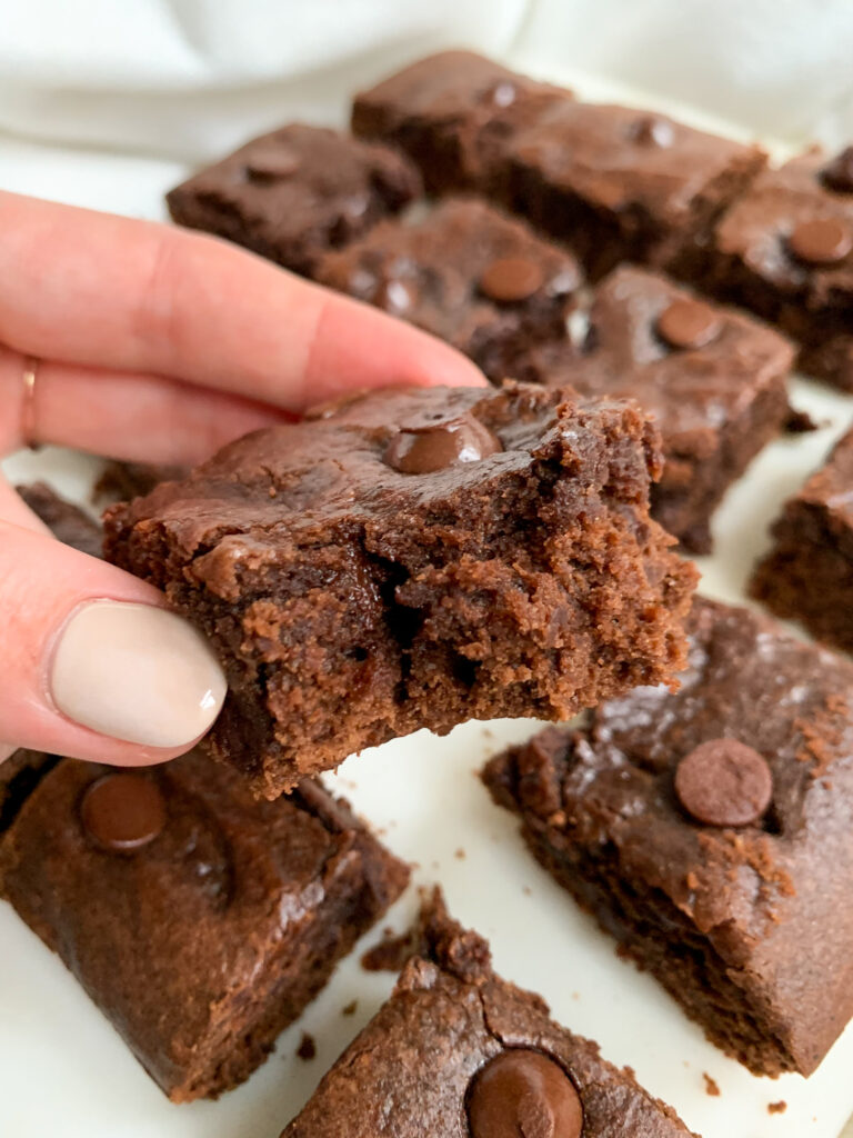easy and healthy brownies on a white board with a hand holding one of them