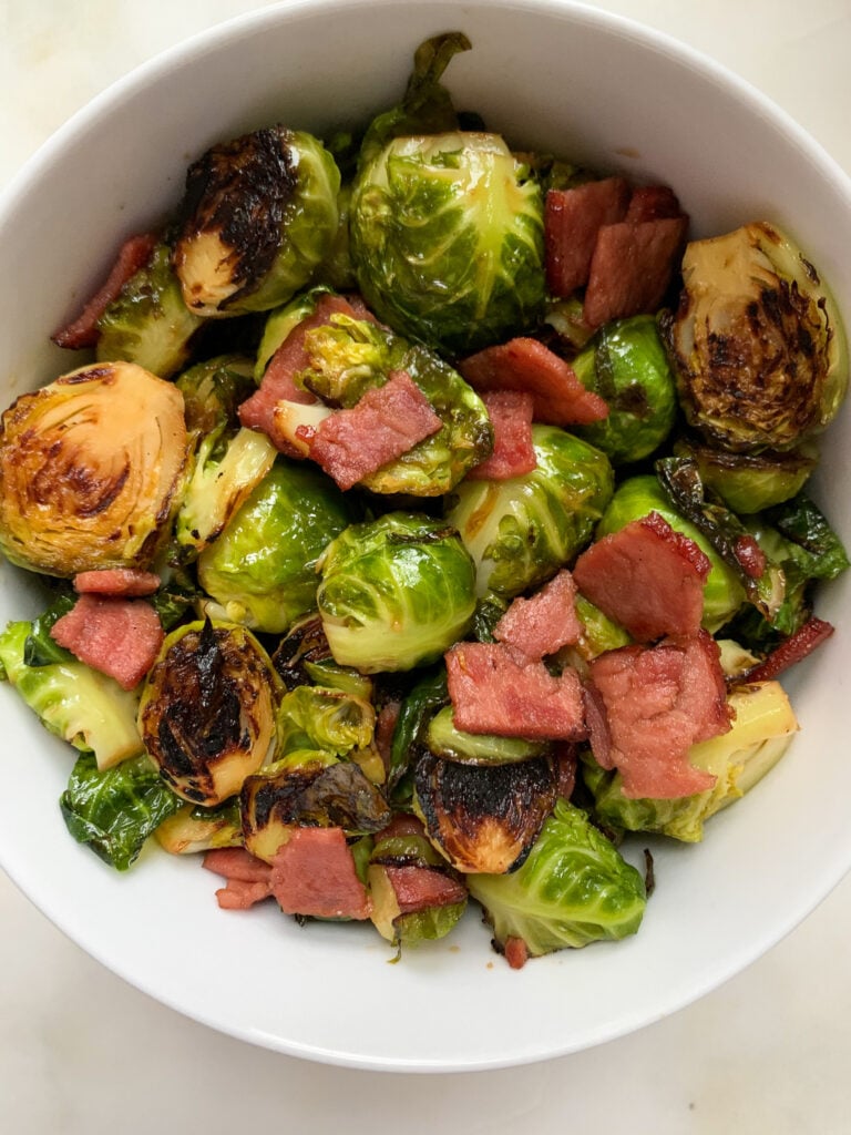 maple balsamic brussels sprouts with turkey bacon in a white bowl on a white background