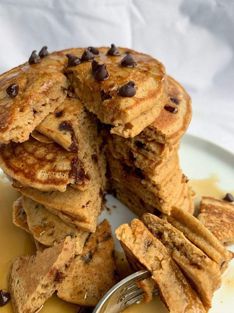 a stack of whole wheat chocolate chip pancakes, with some of the pancakes on a fork