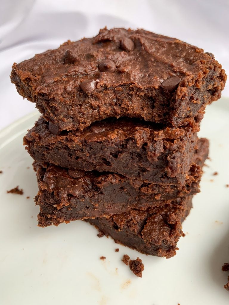 a stack of fudgy vegan chickpea brownies on a white plate