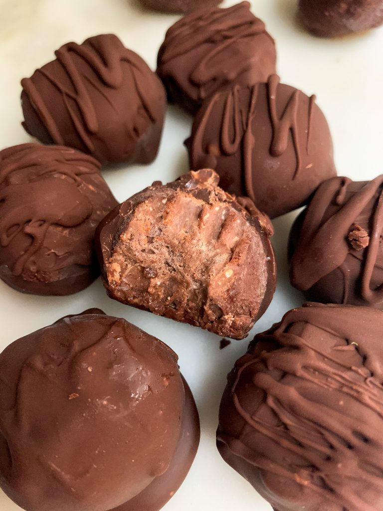brownie batter truffles on a white board, one with a bite taken out of it