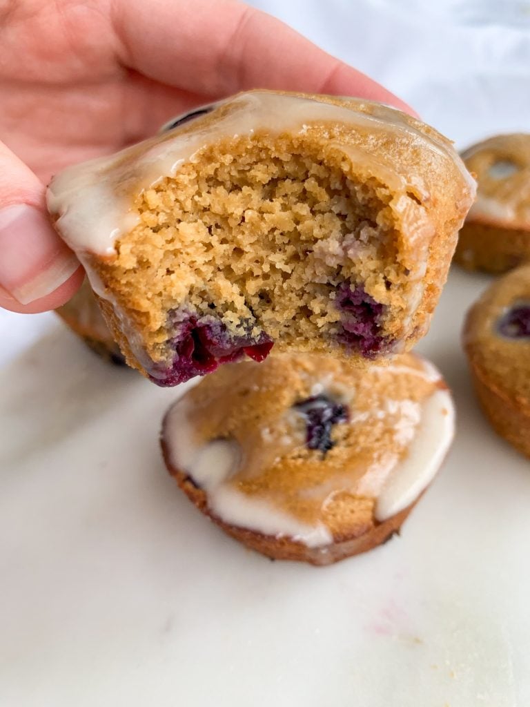 blueberry muffins with lemon coconut glaze, one with a bite taken out of it