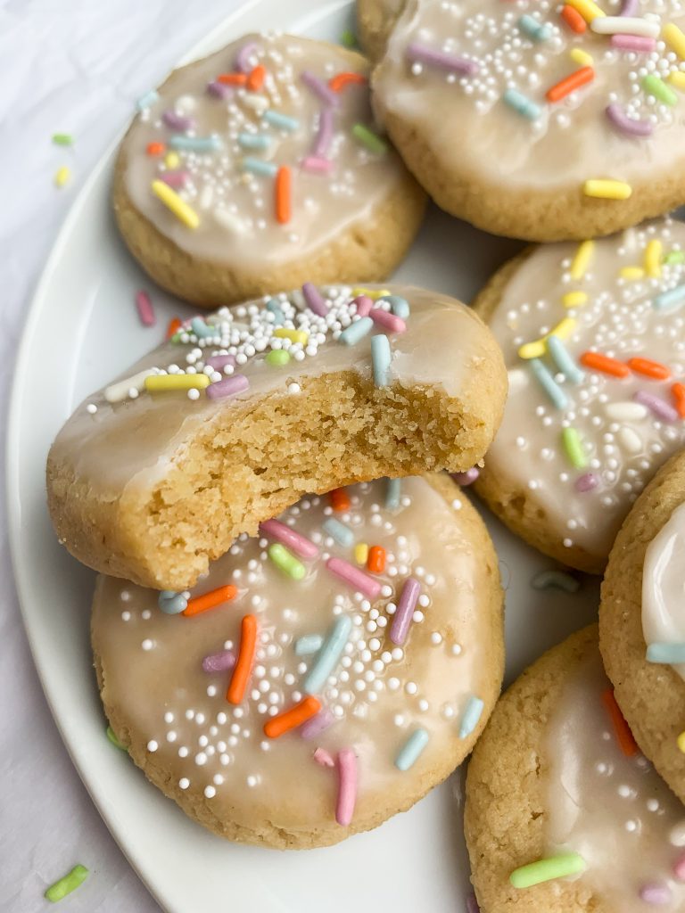 a plate of gluten free sugar cookies with one with a bite taken out 