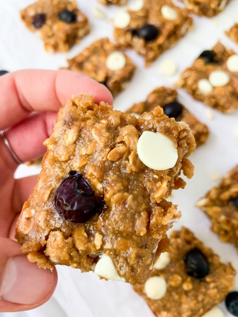 a hand holding on of the oatmeal cookie bars over more bars