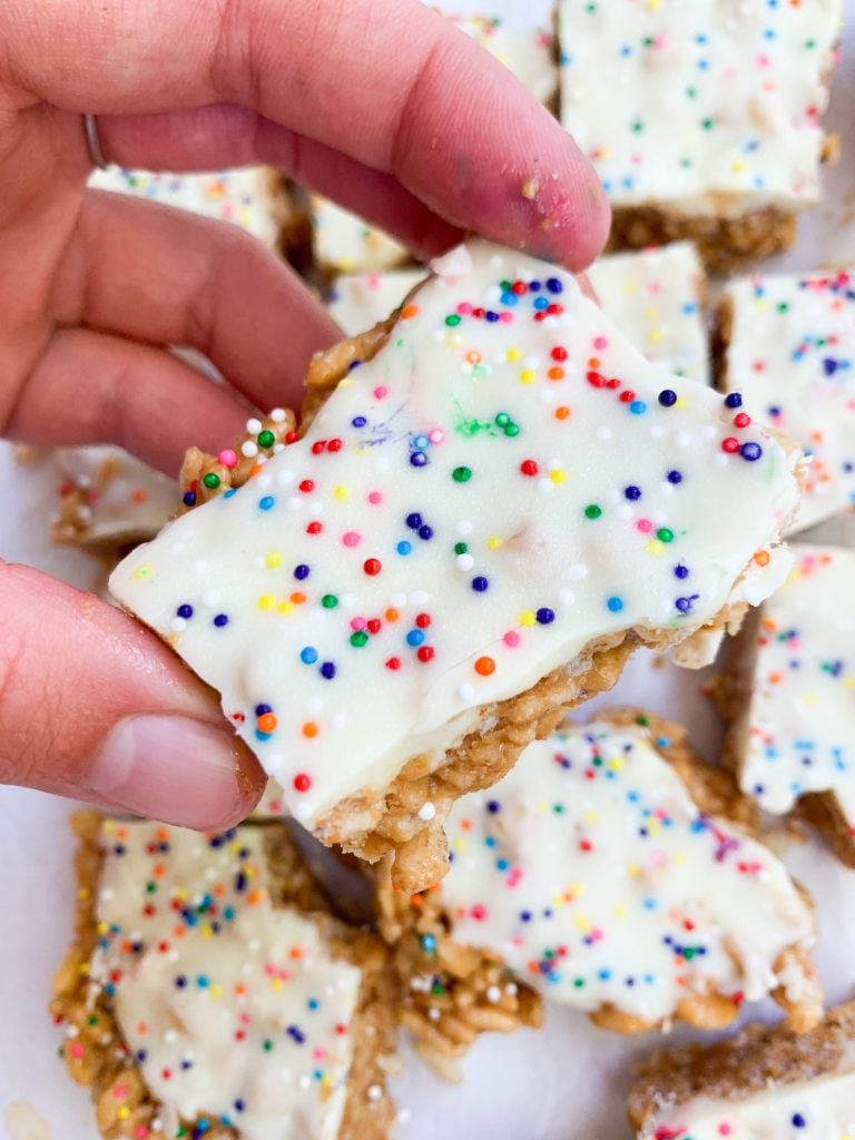 a hand holding one of the birthday cake cereal bars
