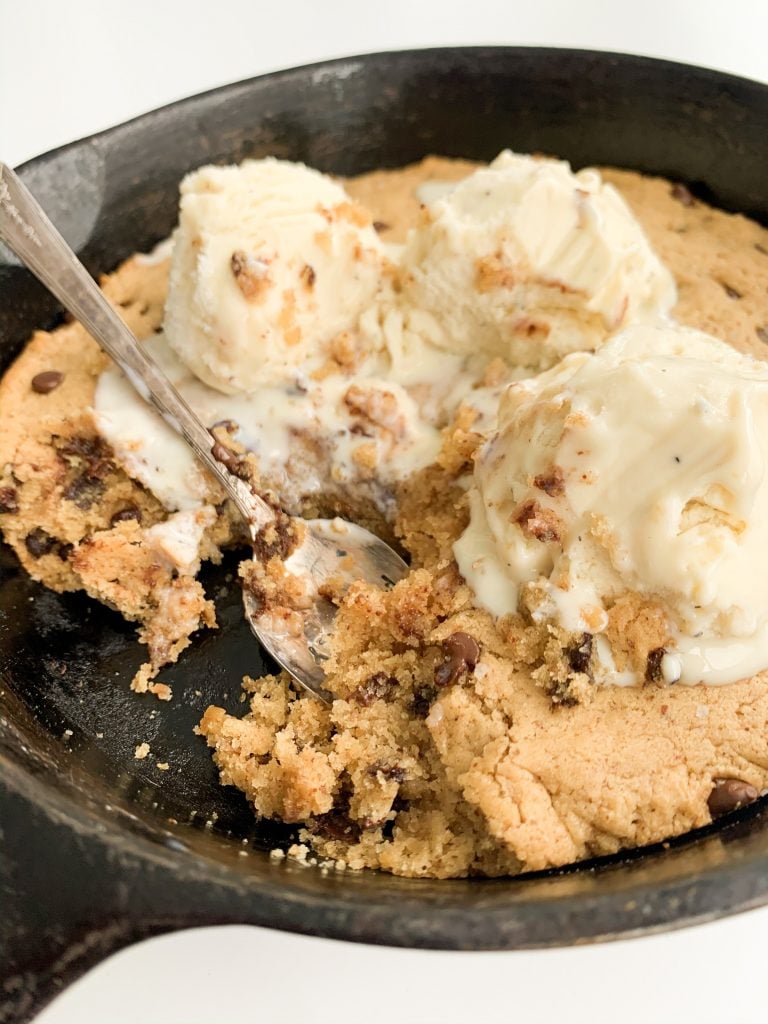 closeup photo of the cookie skillet with melted vanilla ice cream on top and bites taken out of it