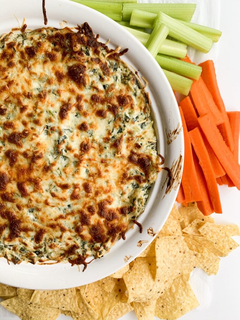 spinach and artichoke dip with carrots, celery, and chips on the side