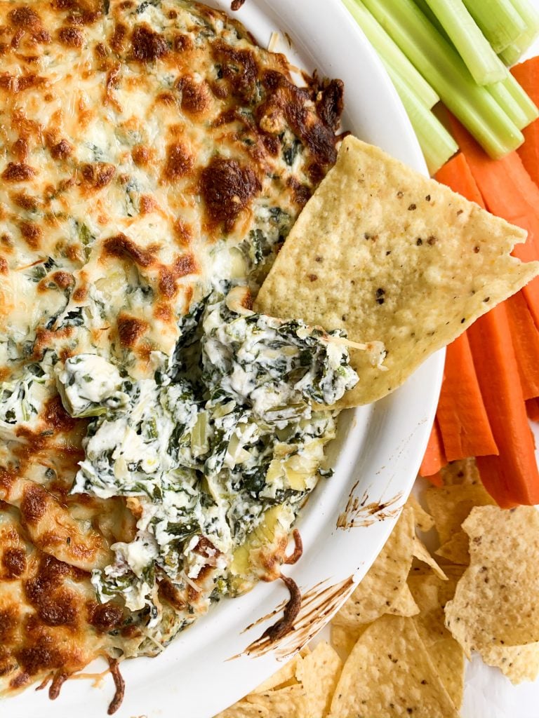 chip dipping into healthy spinach and artichoke dip