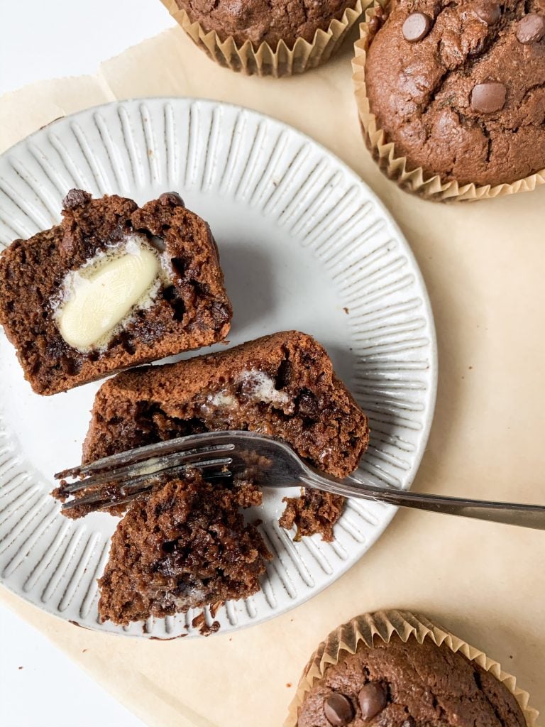 one double chocolate zucchini muffin on a plate with a fork taking a bite