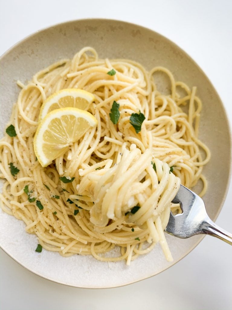 a fork with twirled spaghetti around it over a bowl of lemon parmesan pasta