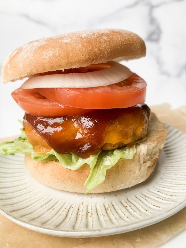 a burger topped with lettuce, tomato, and onion on a grey plate