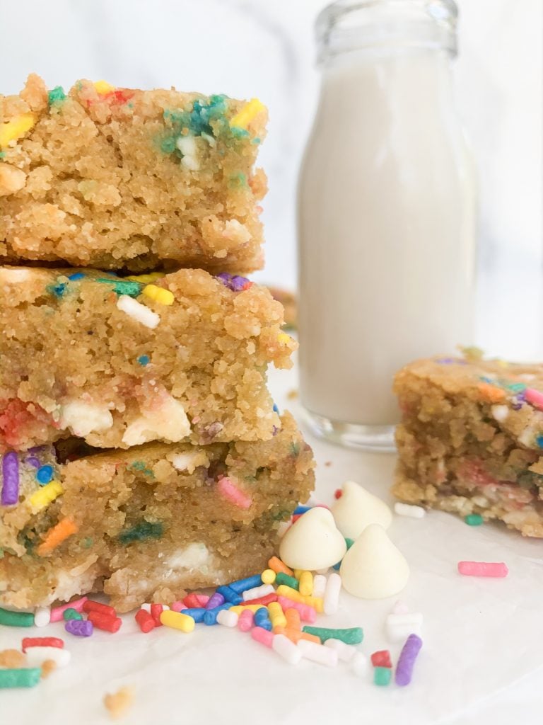 a closeup shot of a stack of blondies and a milk jug in the background