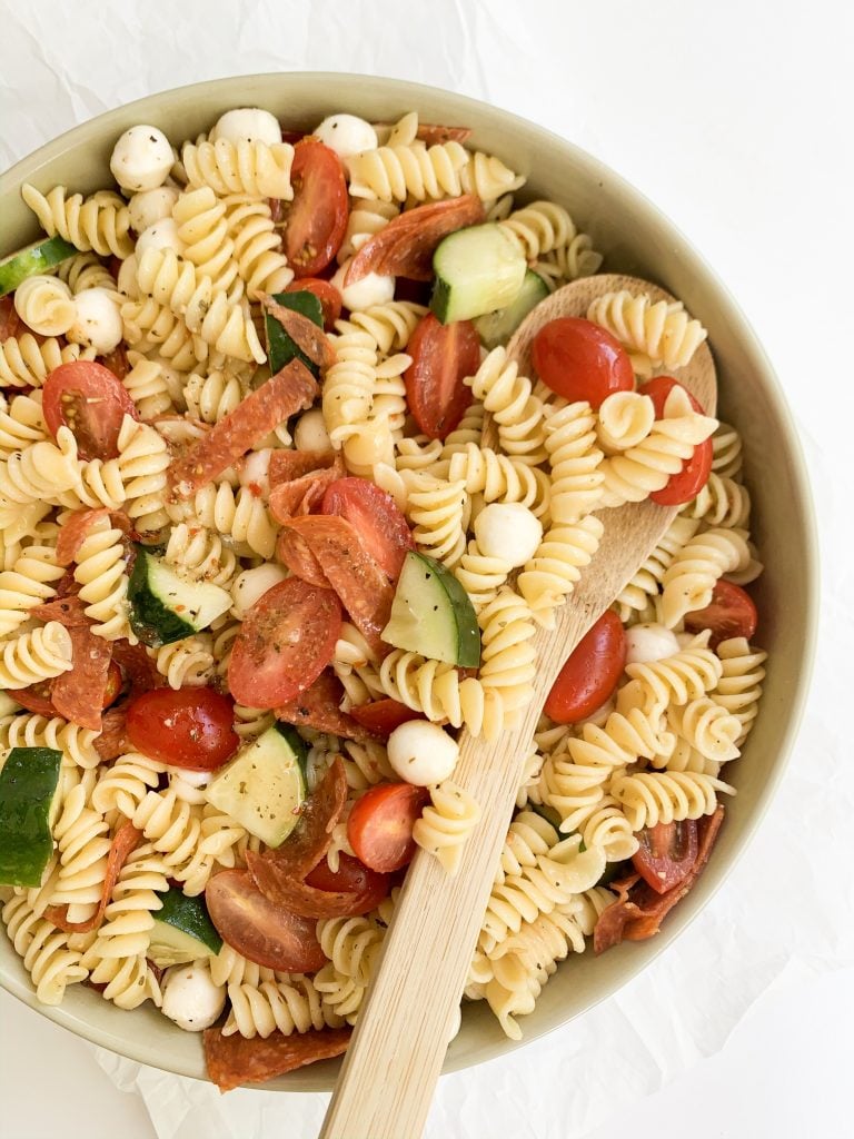 pasta salad in a large bowl with a wooden spoon