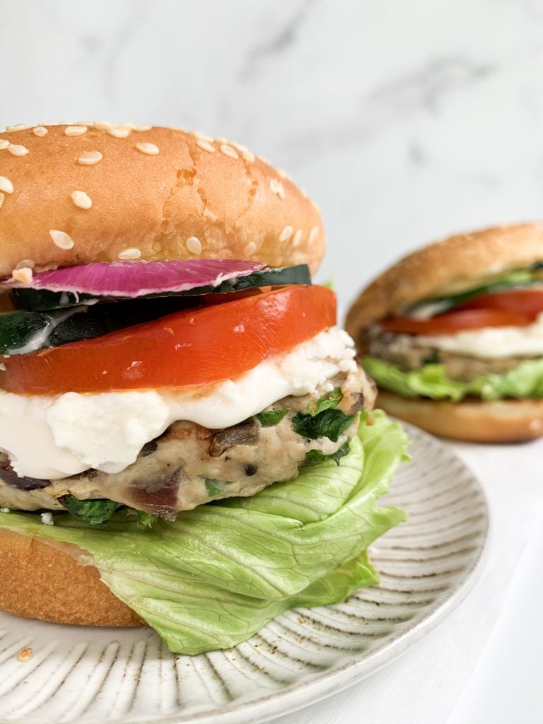 a turkey burger on a bun with tomato, lettuce, onion, and cucumber