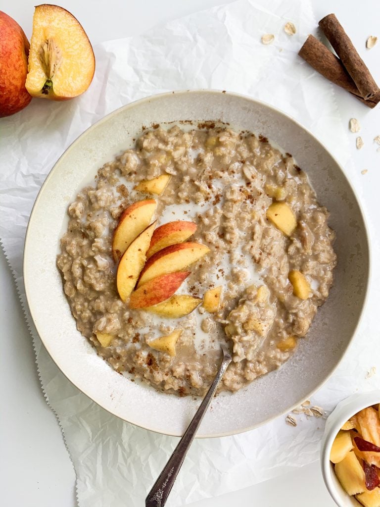 a bowl of peach oatmeal on a white background 
