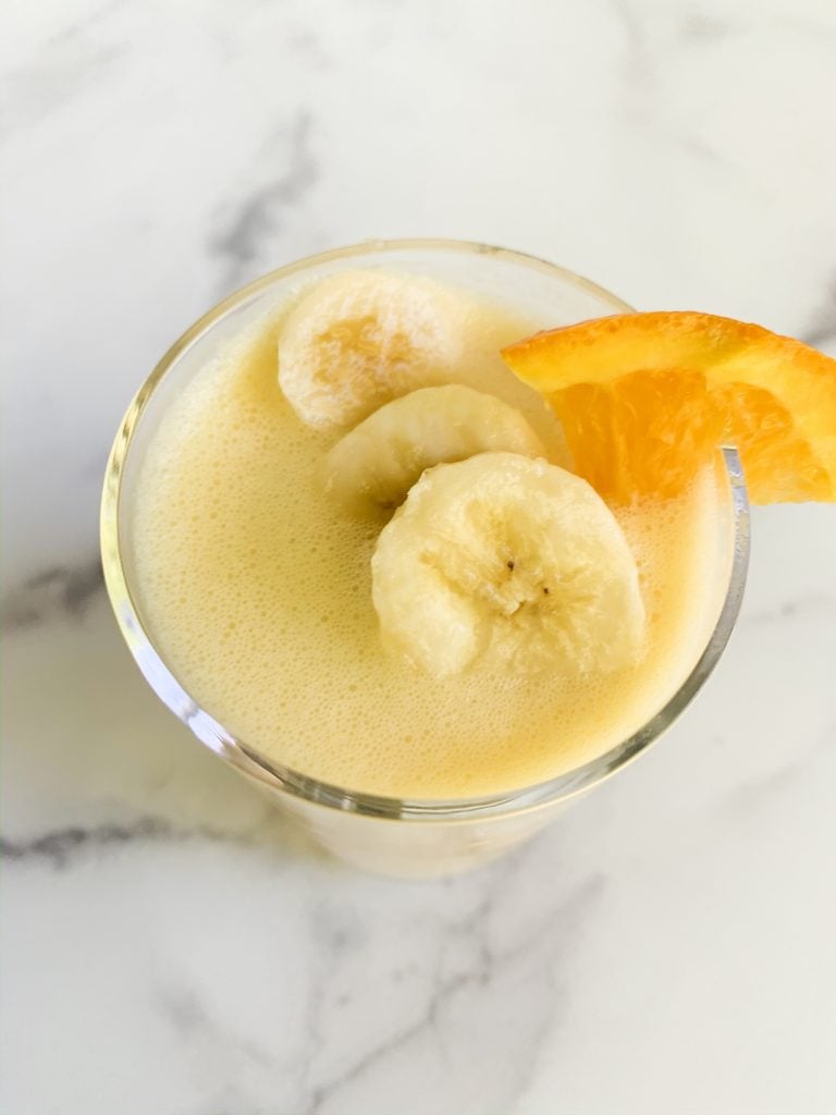 overhead shot of an orange smoothie topped with banana and orange