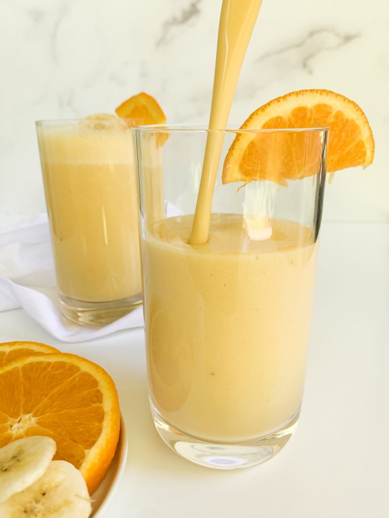 orange banana smoothie being poured into a glass