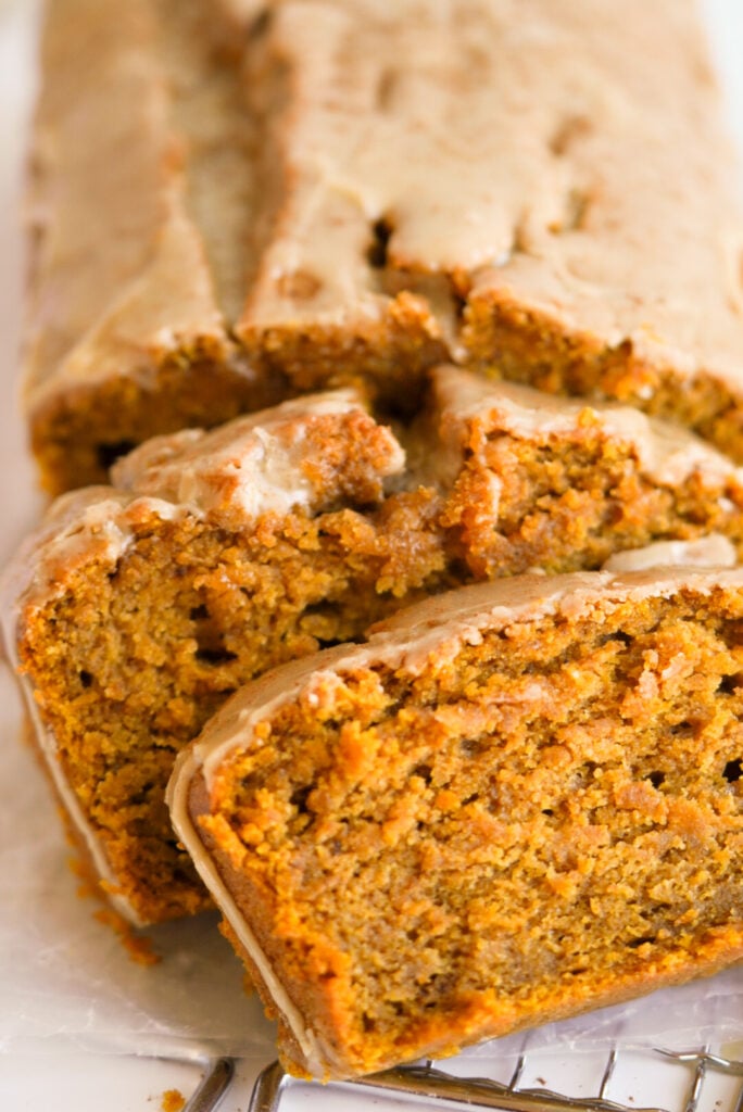 45 degree angle shot of a loaf of Easy Pumpkin Bread with a few slices tilted on an angle.