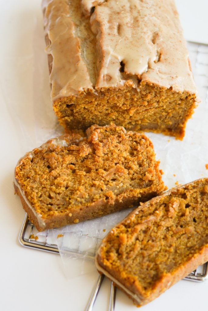 loaf of Pumpkin Bread with Maple Glaze on a cooling rack with two slices taken and turned on their sides.