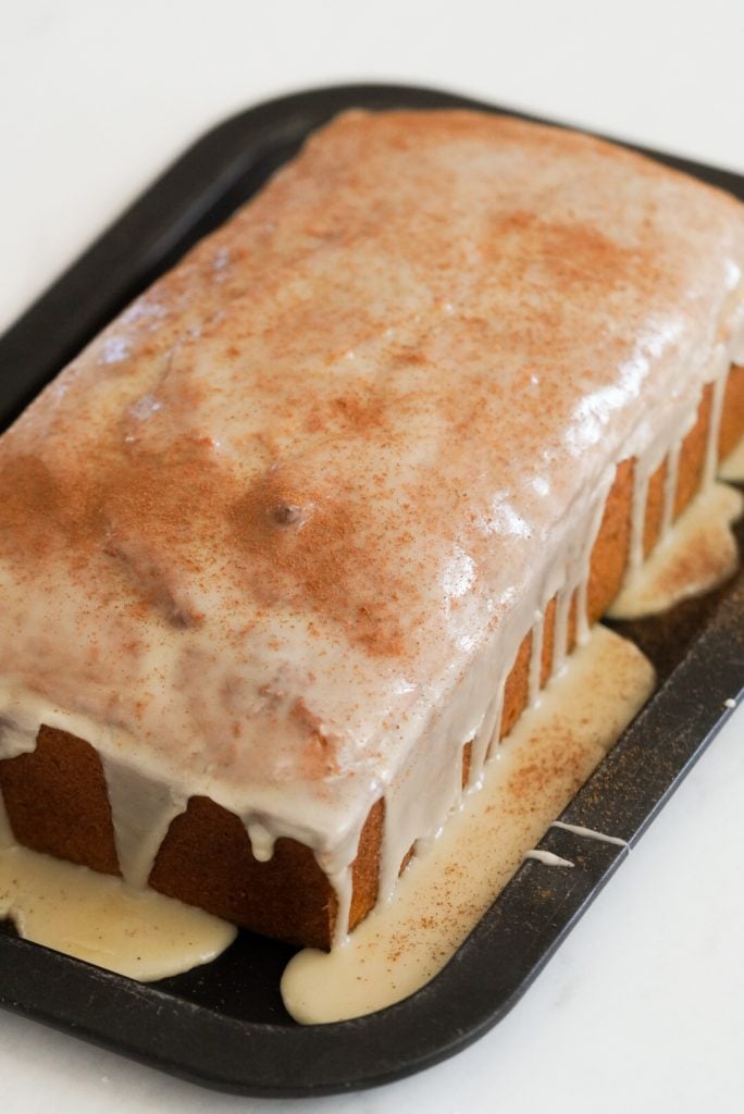 pumpkin bread on a black tray covered in maple glaze