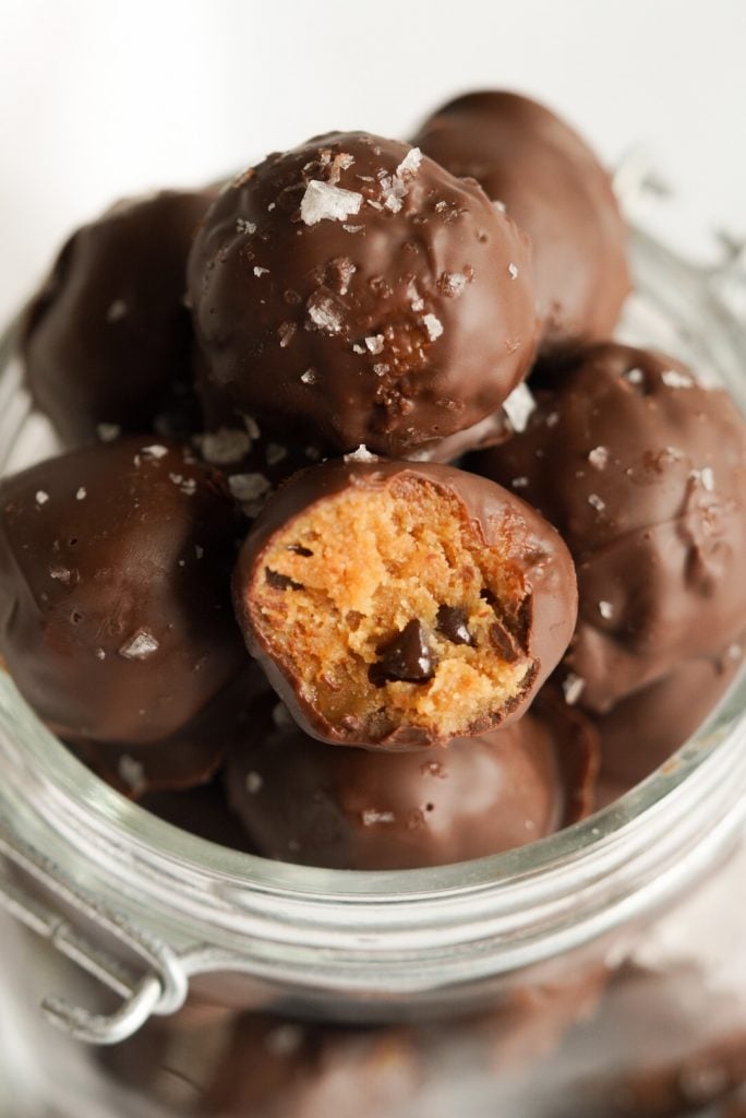 closeup shot of chocolate chip cookie dough bites in a jar with a bite taken out of one