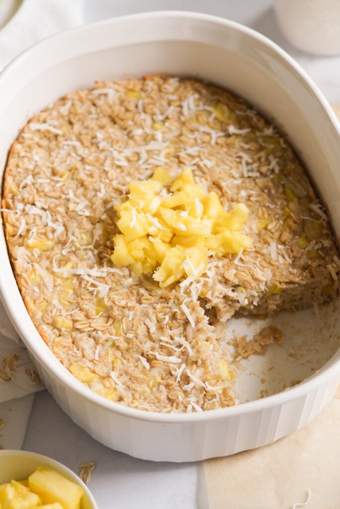 pineapple coconut baked oatmeal in a large baking dish topped with extra pineapple