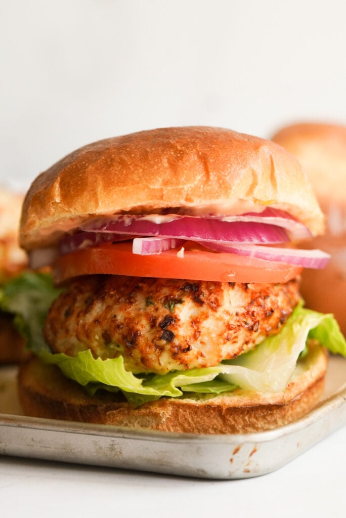 air fryer chicken burger on a bun with tomato, lettuce, and onion