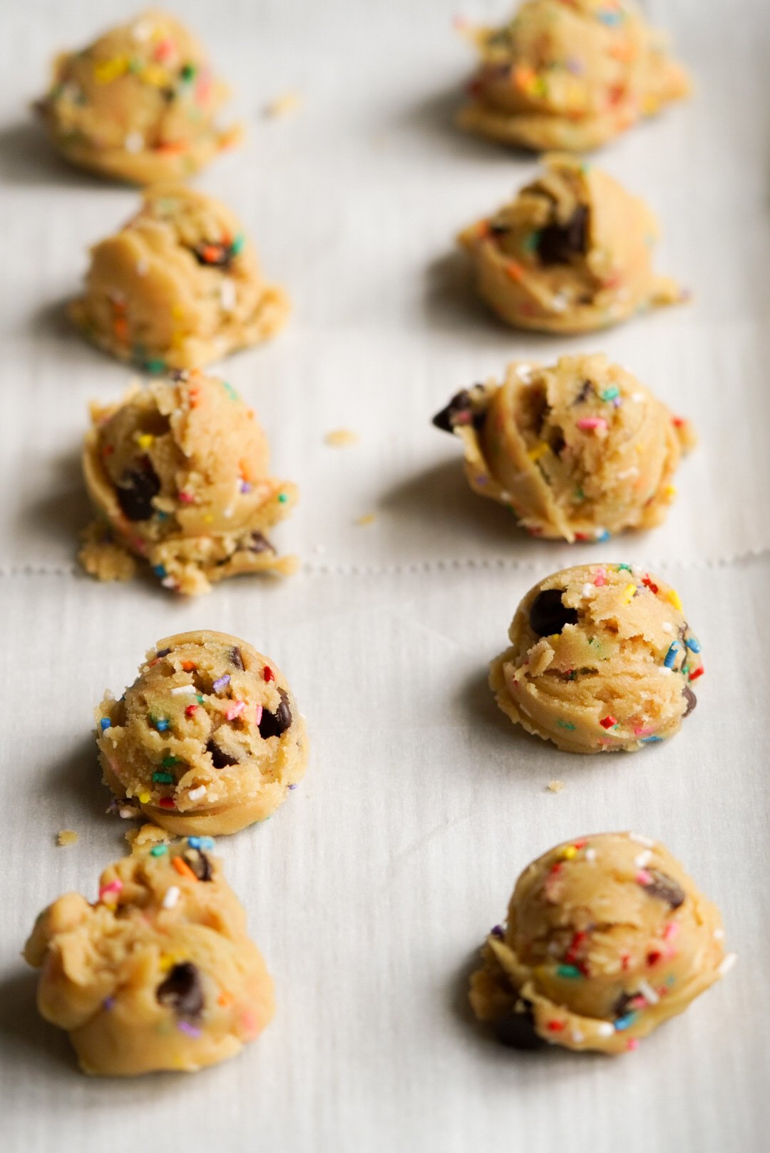 cookie dough balls on a parchment paper lined baking sheet