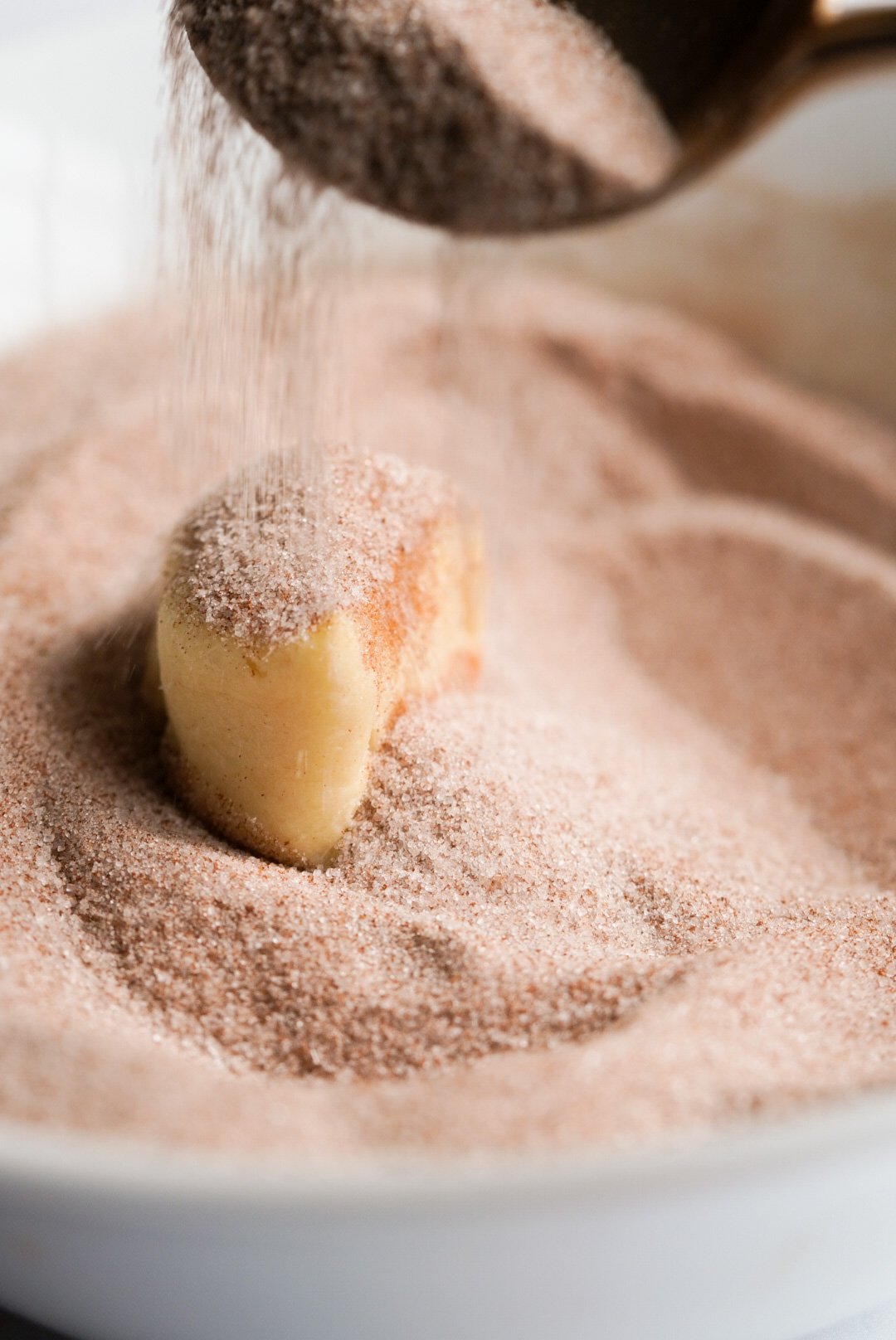 a crescent dough piece being sprinkled with cinnamon sugar