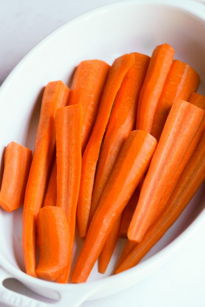 peeled and trimmed carrots in a baking dish