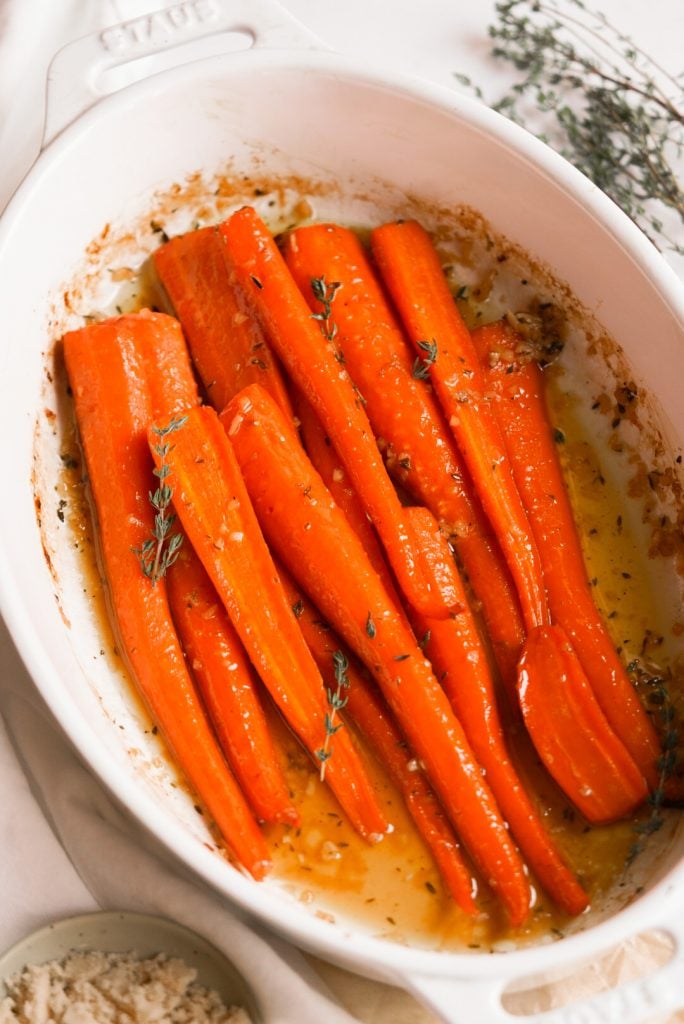 carrots in a baking dish with brown sugar and thyme on the side