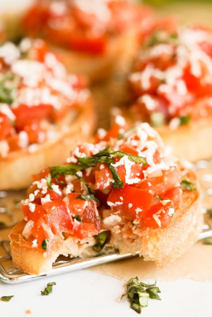 tomato bruschetta topped with goat cheese with a bite taken out
