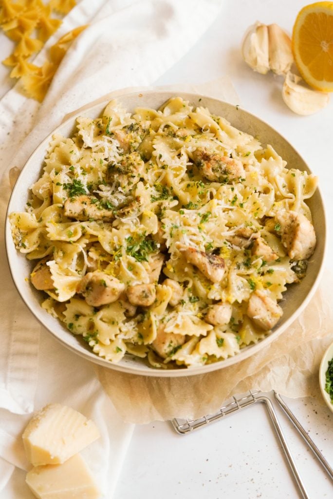 bowl of lemon pasta with cheese, parsley, and lemon on the side