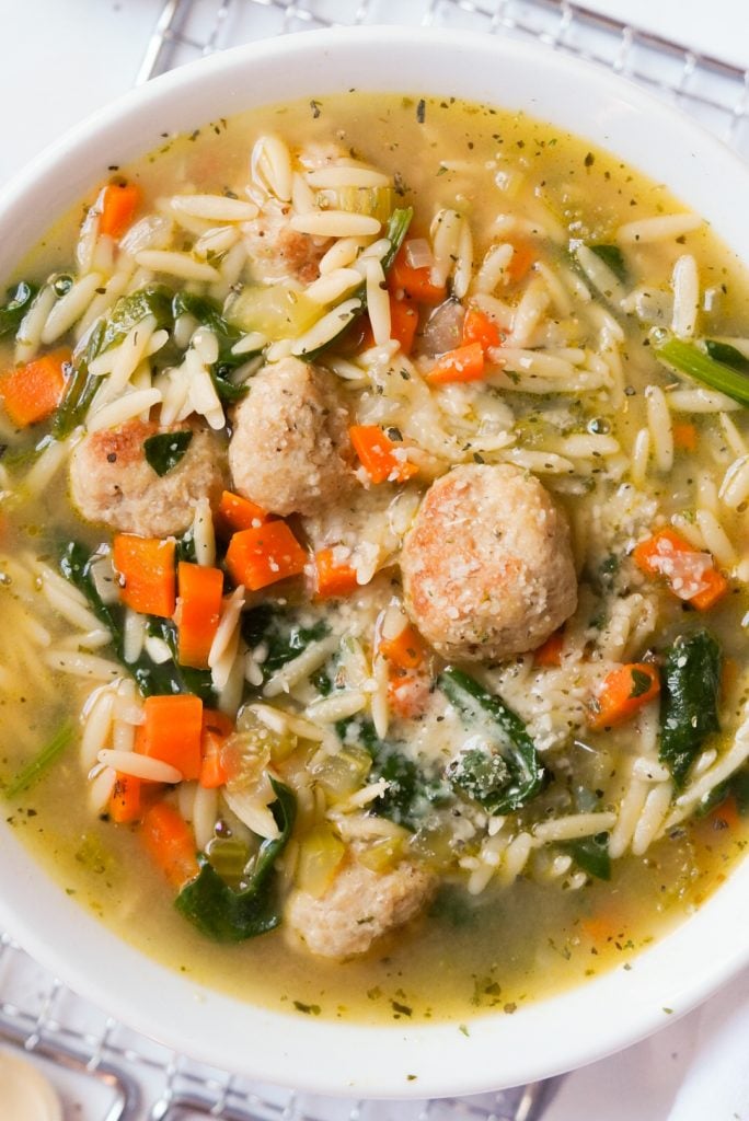 bowl of chicken meatball soup topped with parmesan cheese