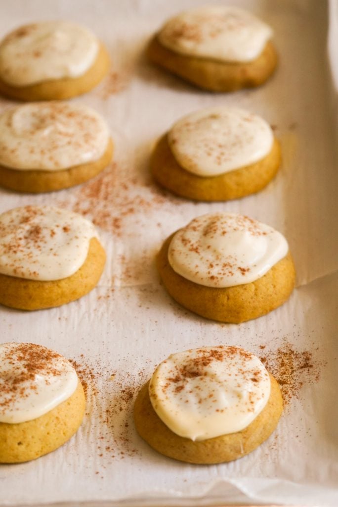 pumpkin sugar cookies with cream cheese frosting on a cookie sheet