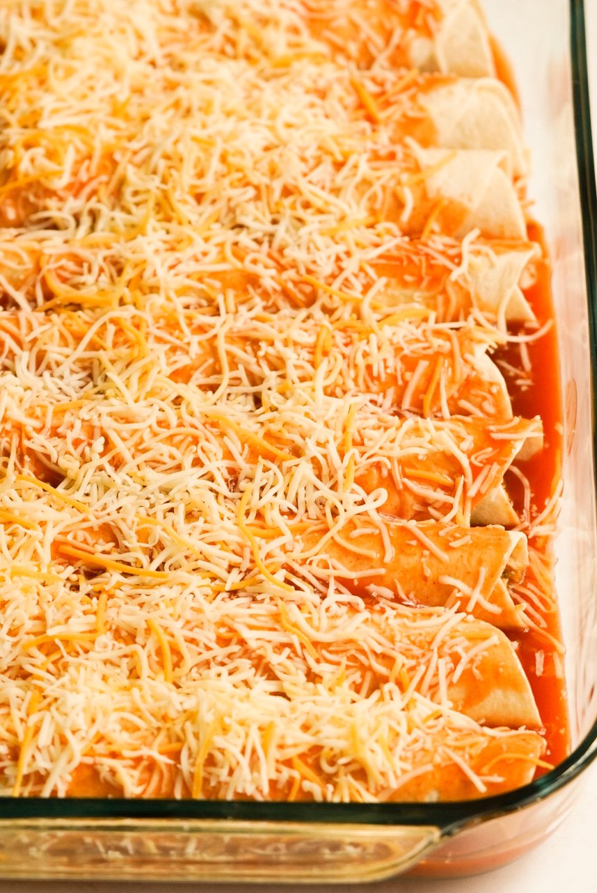 enchiladas covered with sauce and cheese in a baking dish