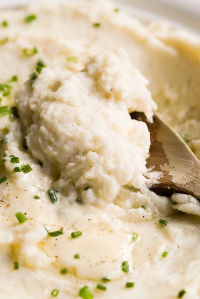 close up shot of wooden spoon scooping mashed potatoes