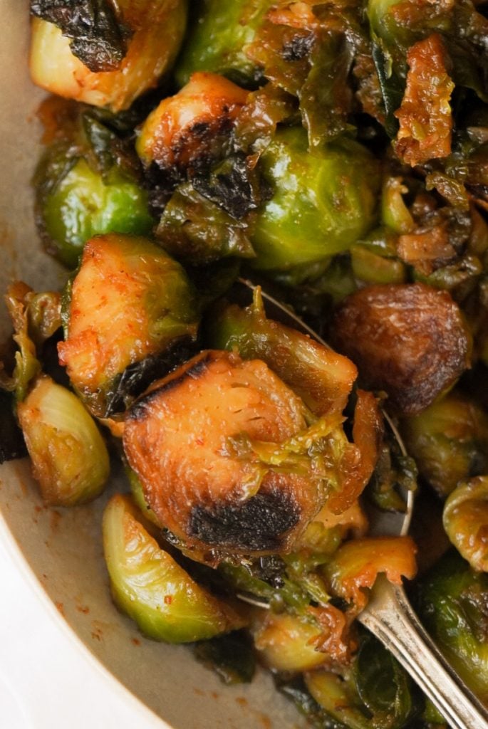 spoonful of brussel sprouts with a sweet and spicy sauce