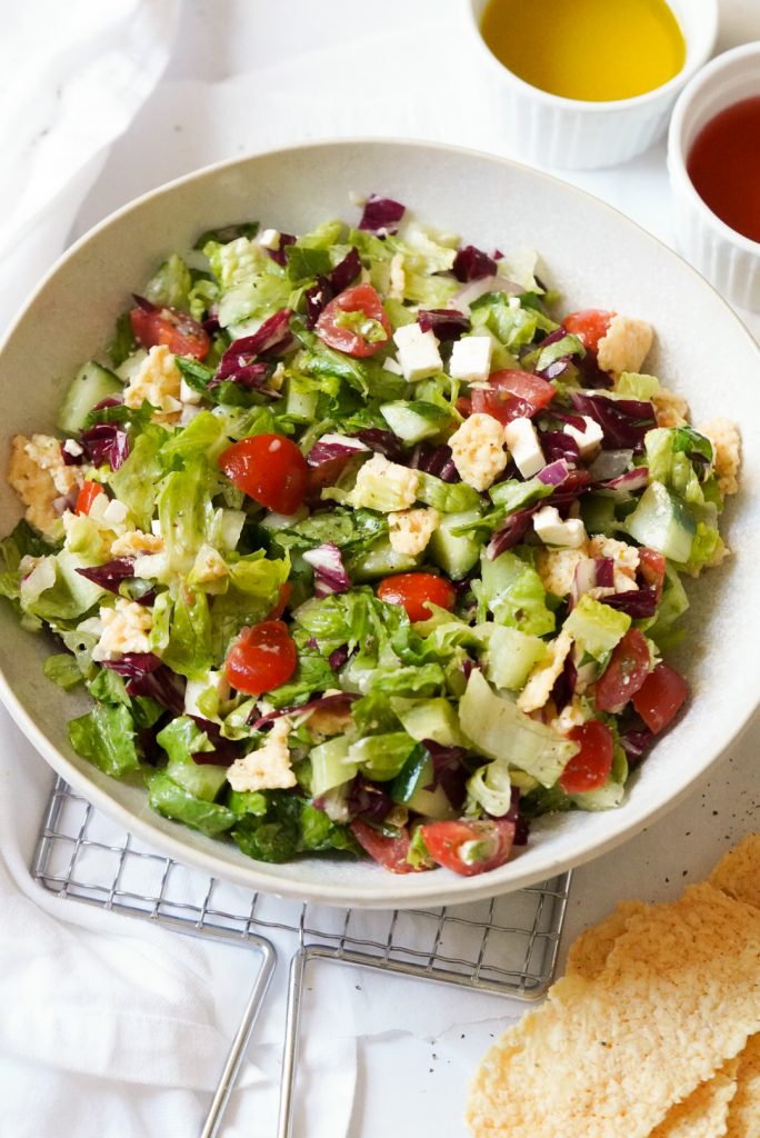 chopped salad with tomatoes, cucumber, red onion, feta, and parmesan crisps