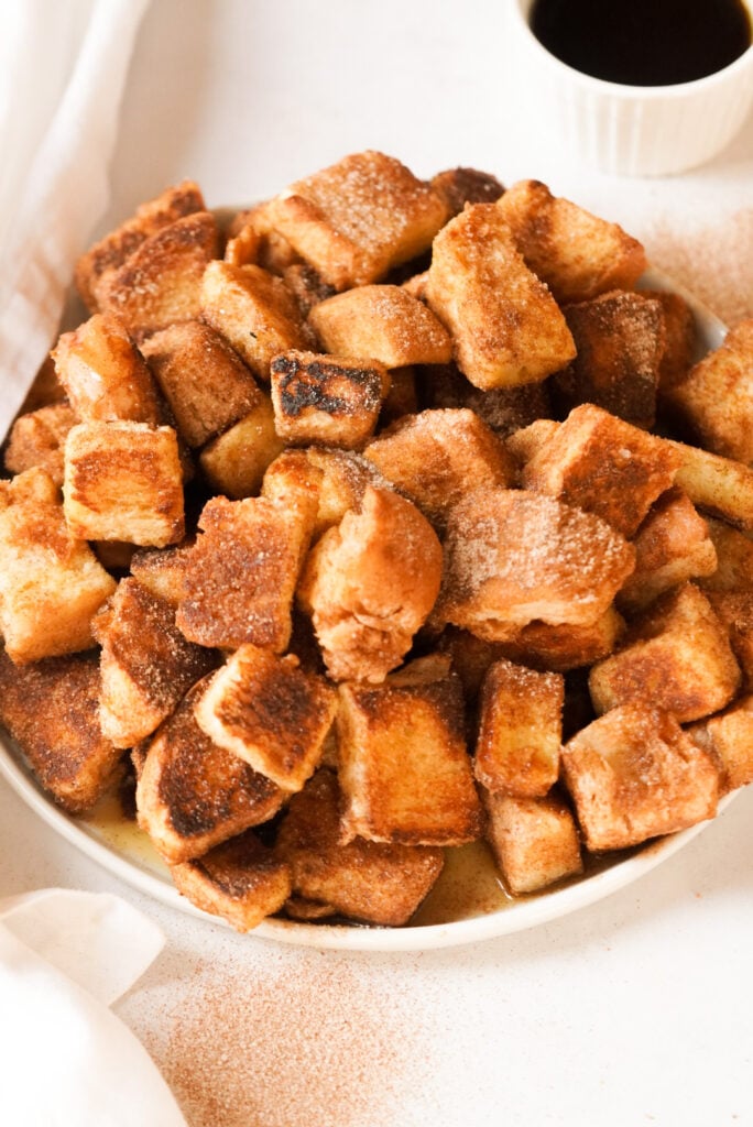 plate with cinnamon sugar french toast cubes and maple syrup on the side