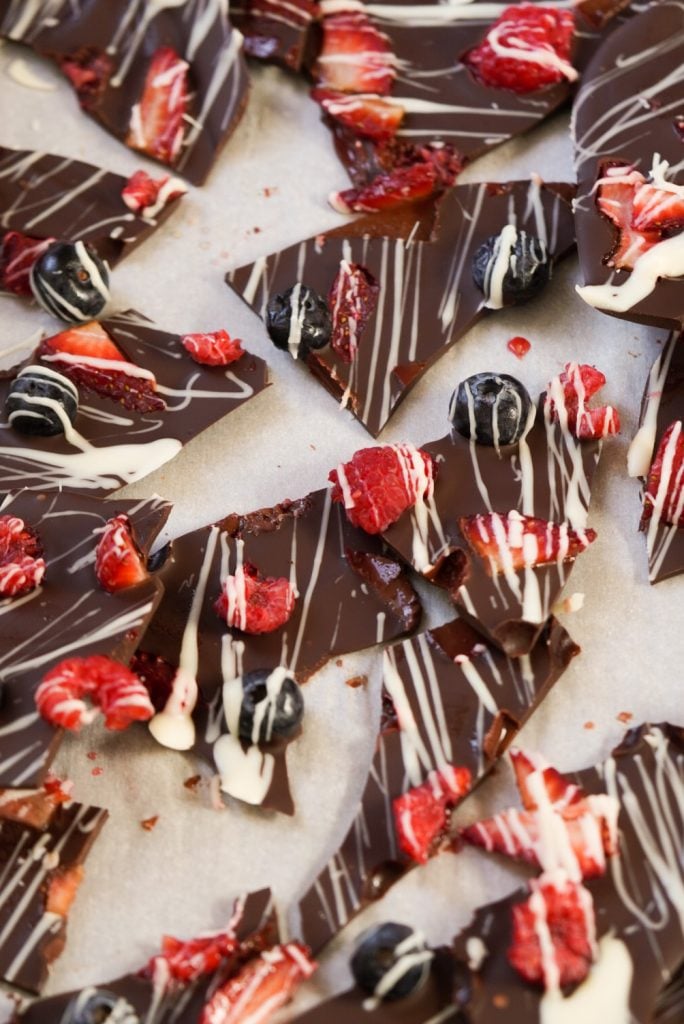 chocolate bark pieces topped with blueberries, raspberries, and strawberries and white chocolate