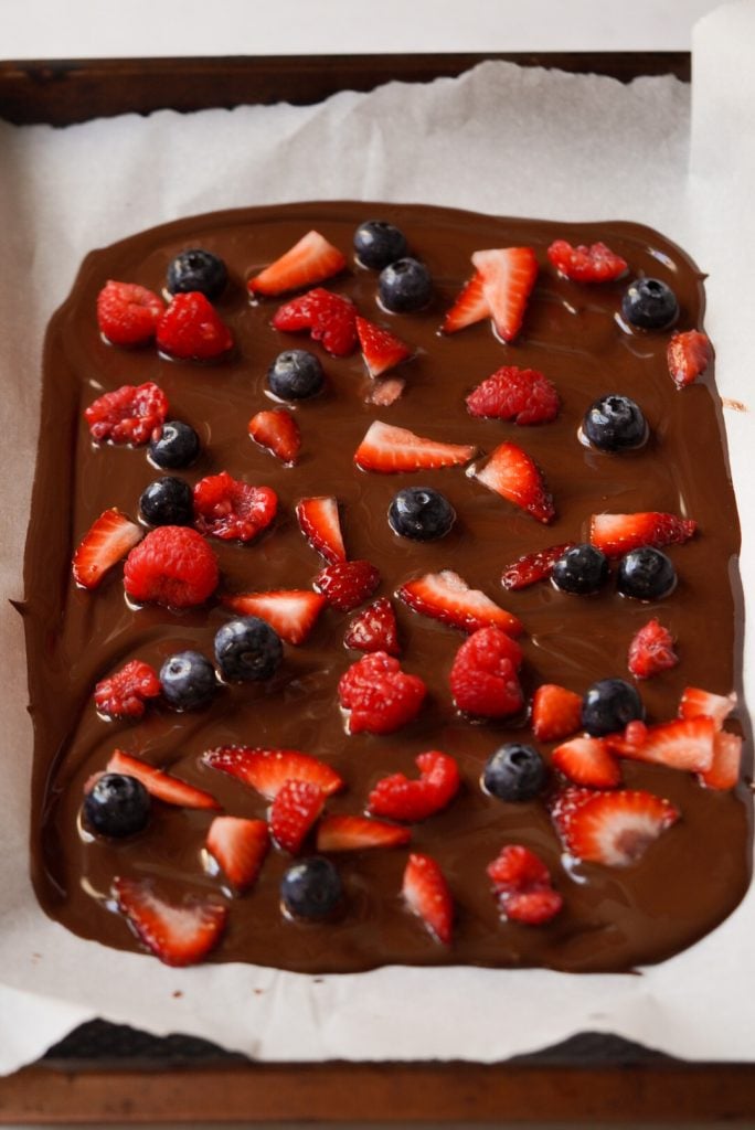 melted dark chocolate topped with mixed berries on a cookie sheet