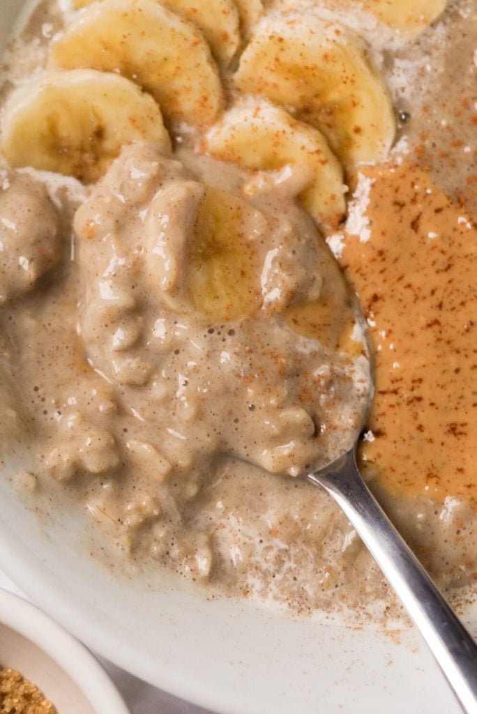 creamy banana oatmeal topped with peanut butter and banana slices