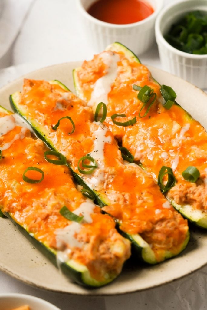 buffalo chicken zucchini boats with ranch dressing and green onions on a plate