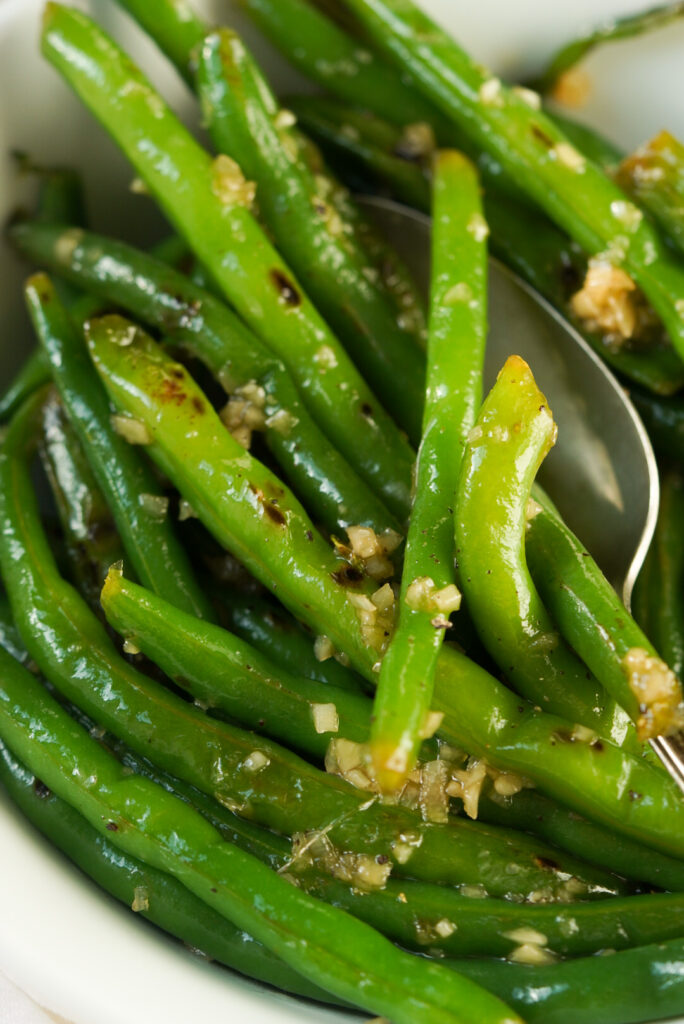honey garlic green beans in a white bowl with a spoon