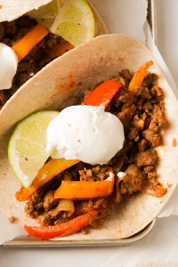 close up shot of a tortillas with ground beef, peppers, and onions